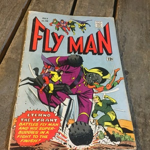Puede incluir: Una portada de cómic vintage con un superhéroe llamado Fly Man con un traje verde y amarillo. La portada presenta a un villano morado llamado Eterno el Tirano luchando contra Fly Man y sus superamigos. La portada del cómic es de julio de 1963 y cuesta 12 centavos.