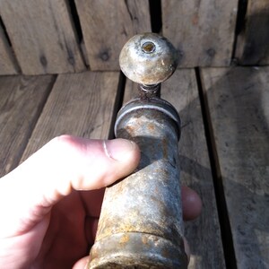 May include: A vintage metal pepper grinder with a round top and a cylindrical body. The grinder is silver with rust spots and has a small hole at the bottom.
