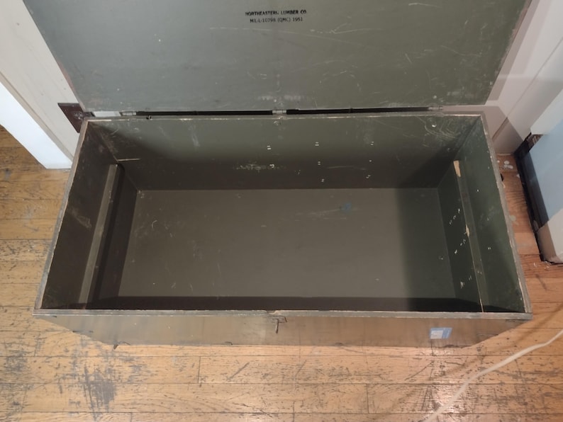 May include: A large, green wooden storage chest with a hinged lid. The chest is empty and the inside is visible. The chest is made of wood and has a metal latch.