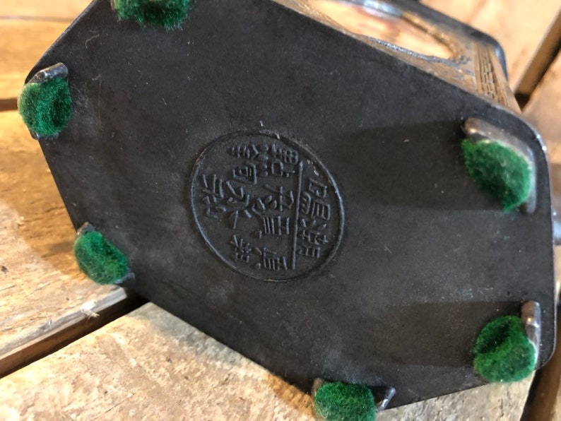 May include: Black hexagonal box with a circular seal on the bottom. The seal has Chinese characters in gold. The box has five green felt feet.