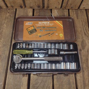 May include: A 40-piece Ludell combination socket set in a brown metal case. The set includes various sockets, a ratchet, and other tools. The case is open, revealing the tools neatly arranged. The text on the case reads "40 Piece 1/4 & 3/8 Drive SAE and Metric Combination Socket Set."