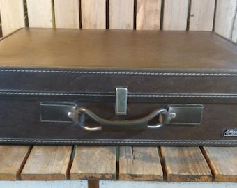 May include: A brown leather suitcase with a metal handle and a brass latch. The suitcase has a label that reads "Alta Moda" in gold lettering.