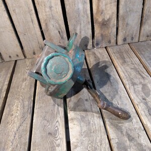 May include: A vintage green metal hand crank with a wooden handle. The crank has a large, round, green metal knob.