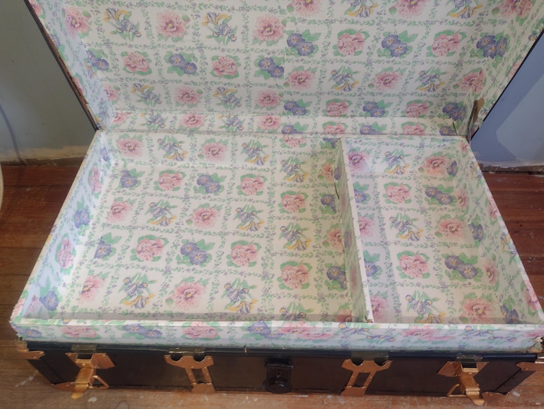 Puede incluir: Un ba&uacute;l de madera vintage con herrajes de lat&oacute;n y un forro con estampado floral. El ba&uacute;l tiene un peque&ntilde;o compartimento en el interior.