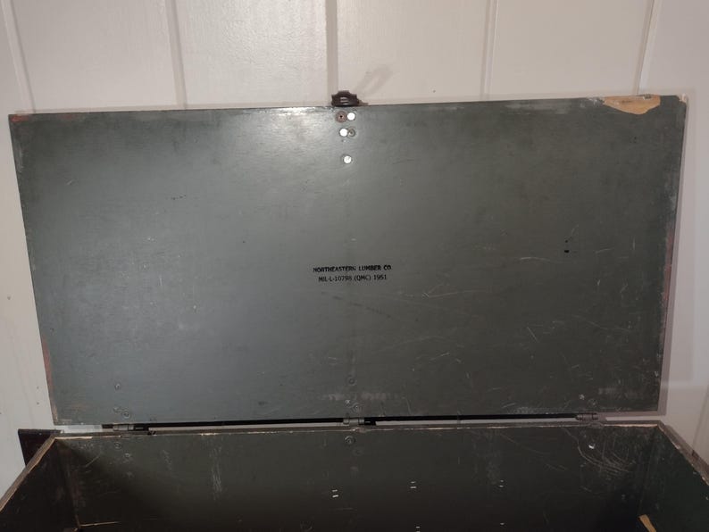 May include: A dark green wooden storage box with a hinged lid. The lid has a label that reads "Northeastern Lumber Co. Mill & Distributing Corp. 1953."