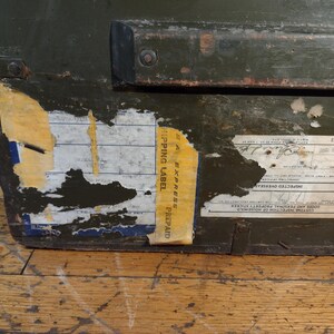 May include: A green wooden box with a black metal handle and a yellow label that says "Express Prepaid Shipping Label". The box has a label with the text "Inspected Overseas Goods and Personal Property Shipped from Homeward", "20.12.1921", and "30.4.1921".