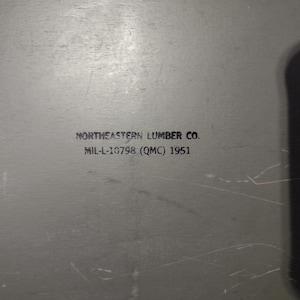 May include: A gray metal box with the text "NORTHEASTERN LUMBER CO. MIL-L-10798 (QMC) 1951" printed on the front.