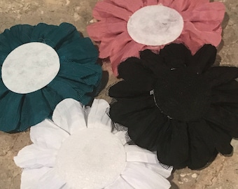 May include: Four fabric flowers with white centers. The flowers are teal, pink, white, and black.
