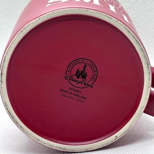 Puede incluir: Una taza de cer&aacute;mica de color rosa oscuro con texto blanco en el lateral que dice YOU A SPECIAL MAKING SMILE. La base presenta un logotipo negro de Disney Parks, el texto AUTHENTIC ORIGINAL, &copy;DISNEY, MADE IN THAILAND y el c&oacute;digo F784-1014-1-12193.