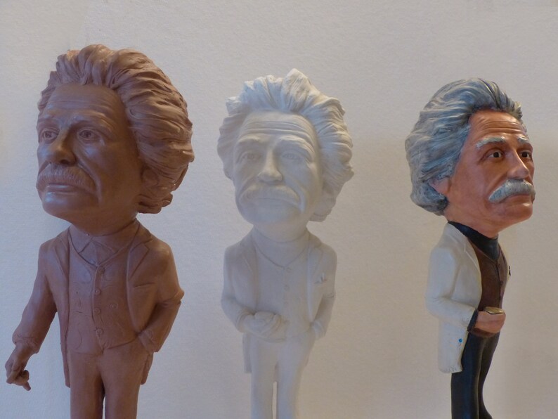 May include: Three ceramic figurines of men with different hair styles and colors. The figurine on the left is brown, the figurine in the middle is white, and the figurine on the right is brown and white.