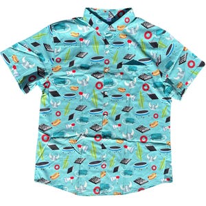 May include: A short-sleeved button-down shirt with a light blue background and a repeating pattern of various objects. The pattern includes hot dogs, bull horns, megaphones, and other shapes in red, black, and green.