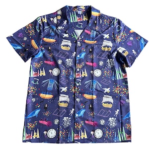 May include: Short-sleeved button-down shirt in a dark blue hue, adorned with a whimsical pattern of various illustrations. The design includes images of boats, clocks, hot dogs, and other playful elements. The shirt has a classic collar and a single chest pocket.