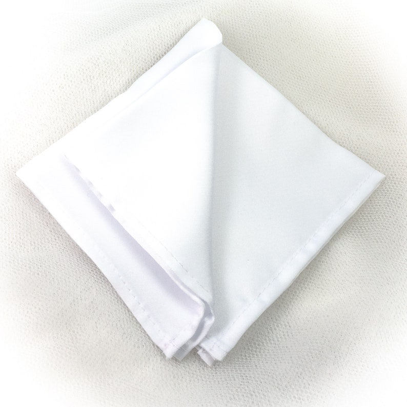 May include: A folded white pocket square, made of a smooth fabric, is displayed against a white background. The square is neatly folded, showcasing its clean lines and crisp edges. The pocket square is a classic accessory.