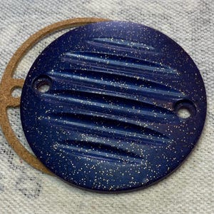 May include: A round, blue metal cover with a textured surface and gold glitter. The cover has two holes on the side.