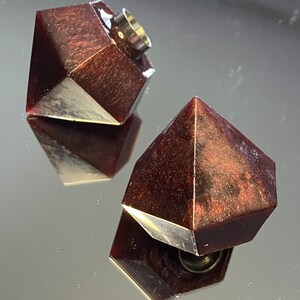Può includere: Due tappi per bottiglia di colore rosso scuro a forma di diamante con un bordo argentato. I tappi hanno un foro nella parte superiore per inserire una bottiglia.