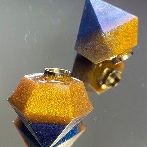 Può includere: Due tappi per bottiglia a forma di diamante in resina dorata e blu. I tappi hanno una finitura scintillante.