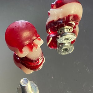 Peut inclure: Deux poignées de tiroir en forme de crâne rouge et blanc avec une quincaillerie de montage en métal argenté.