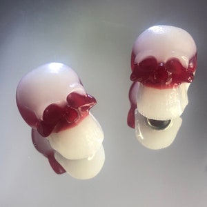 Peut inclure: Deux moules à bonbons en forme de crâne blancs avec des détails rouges. Les moules sont faits d'un matériau translucide et ont une finition brillante.