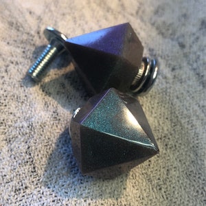 May include: Two dark gray diamond-shaped cabinet knobs with a silver screw and spring. The knobs have a glittery finish.
