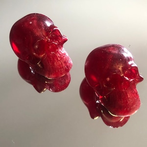 Peut inclure: Deux petites figurines de crâne en résine rouge. Les crânes sont détaillés et ont une finition brillante.