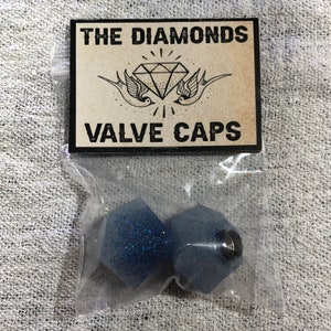 May include: Two blue glitter valve caps in a clear plastic bag with a white card that says "THE DIAMONDS VALVE CAPS" with a diamond and two birds.