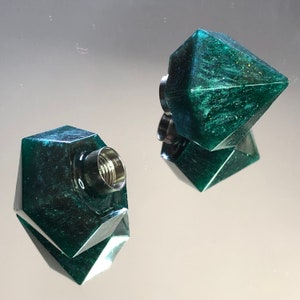 Può includere: Due tappi per bottiglia di forma geometrica verde scuro con finitura metallica. Un tappo ha un'apertura filettata.