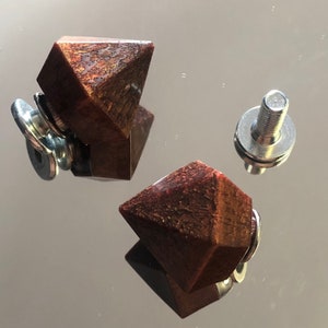 Peut inclure: Deux boutons en bois en forme de diamant avec une base métallique et une vis. Les boutons sont de couleur brun rouge foncé avec un léger chatoiement.