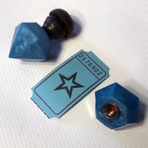 May include: Two blue resin bottle stoppers with a star-shaped ticket with the number 2176902 printed on it.