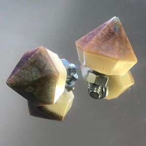 Peut inclure: Deux objets en résine décoratifs en forme de diamant avec une finition argentée métallique. Chaque objet a une vis en métal au centre.