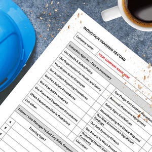 以下が含まれることがあります： 「INDUCTION TRAINING RECORD」と「YOUR COMPANY NAME HERE」のテキストが印刷された、誘導訓練記録。この文書には、さまざまな安全手順が記載されています。青いヘルメットとコーヒーカップが背景にあります。