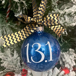 May include: Blue glitter Christmas ornament with a white ribbon and the number "13.1" written on it.