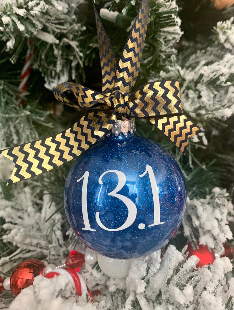 May include: Blue glitter Christmas ornament with a white ribbon and the number "13.1" written on it.