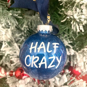 May include: A blue glitter Christmas ornament with the text "HALF CRAZY" in white lettering.