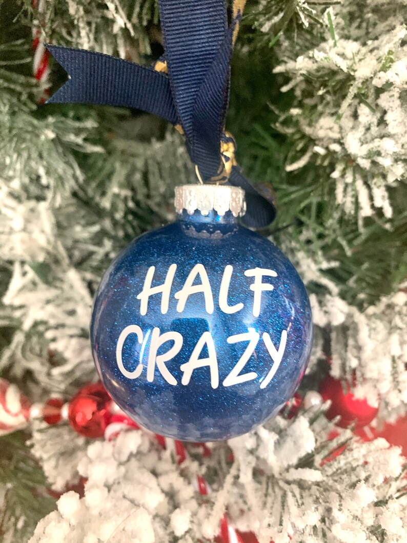 May include: A blue glitter Christmas ornament with the text "HALF CRAZY" in white lettering.