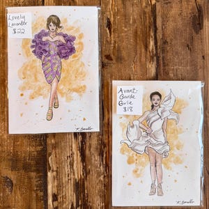 Peut inclure: Deux illustrations de mode sur papier. L'une repr&eacute;sente une femme dans une robe violette avec un grand col &agrave; volants, intitul&eacute;e "Lovely Lavender". L'autre montre une femme dans une robe blanche, intitul&eacute;e "Avant-Garde Girlie".
