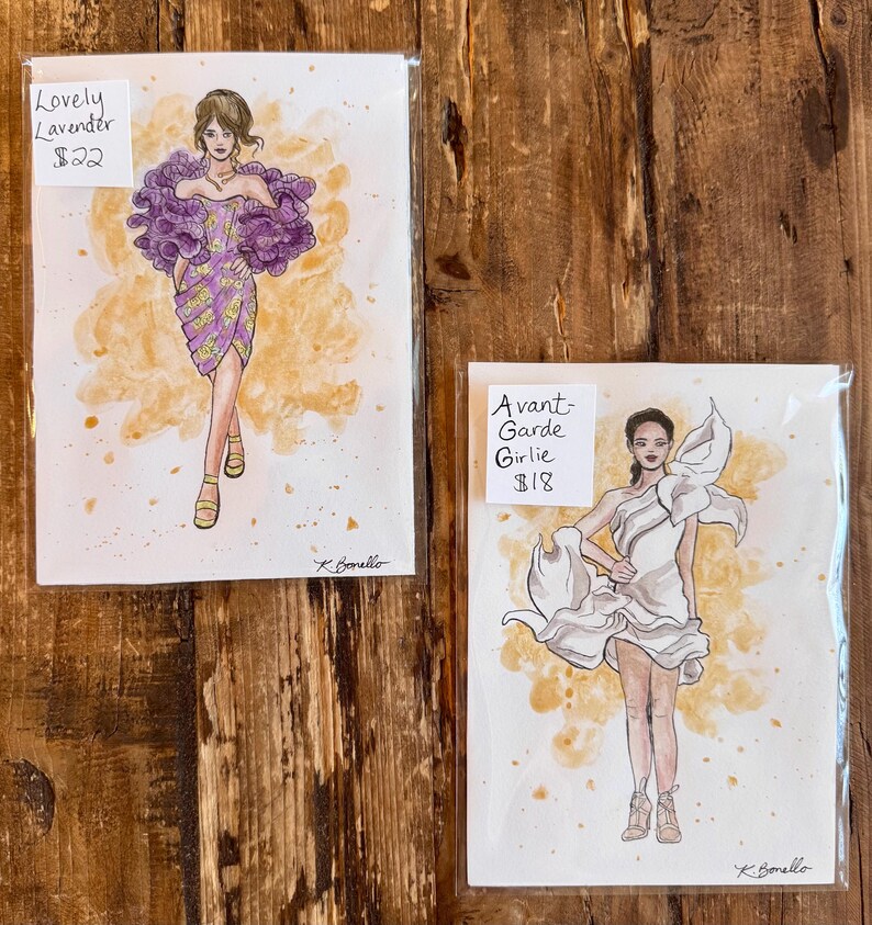 Peut inclure: Deux illustrations de mode sur papier. L'une repr&eacute;sente une femme dans une robe violette avec un grand col &agrave; volants, intitul&eacute;e "Lovely Lavender". L'autre montre une femme dans une robe blanche, intitul&eacute;e "Avant-Garde Girlie".