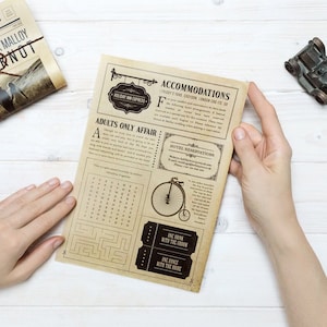 May include: A vintage-style newspaper with the headline "The Wedding Times" and the text "Heather Stones & Patrick Malloy Tying the Knot". The newspaper is folded in half and has a brown twine tied around it. The newspaper is on a white wooden surface.