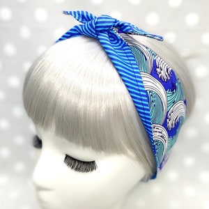 Pode incluir: Faixa de cabeça azul e branca com um padrão de ondas. A faixa de cabeça é amarrada em um nó no topo.