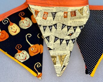 May include: A Halloween banner with three triangular flags. The first flag is black with orange and white pumpkins, the second flag is cream with black text that reads "Eat Treat" and the third flag is black with white polka dots.