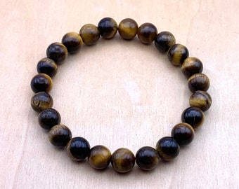 May include: A brown and gold tiger's eye beaded bracelet. The bracelet is made of round beads and is approximately 7 inches in length.