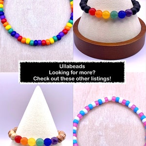 Puede incluir: Cuatro pulseras de cuentas de diferentes colores arco&iacute;ris. La primera pulsera est&aacute; hecha de peque&ntilde;as cuentas redondas en un patr&oacute;n de arco&iacute;ris. La segunda pulsera est&aacute; hecha de cuentas negras con cuentas redondas m&aacute;s grandes de color arco&iacute;ris. La tercera pulsera est&aacute; hecha de cuentas de madera con cuentas redondas m&aacute;s grandes de color arco&iacute;ris. La cuarta pulsera est&aacute; hecha de peque&ntilde;as cuentas redondas en un patr&oacute;n rosa y azul. El texto "Ullabeads Looking for more? Check out these other listings!" se muestra sobre un fondo negro.