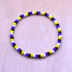 May include: A beaded bracelet with alternating purple, yellow, white, and black beads.