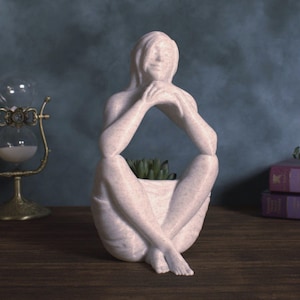 May include: A set of three ceramic mugs with a speckled, matte finish. The mugs are in shades of cream, light gray, and dark gray. Each mug has a simple, minimalist design, perfect for coffee or tea.