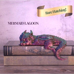 May include: A colorful, iridescent dragon figurine resting on two antique books. The dragon is primarily purple, green, and blue. The text "MERMAID LAGOON" is below the dragon, and a banner above reads "Rare Hatching!"