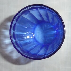 May include: A cobalt blue glass bowl with a fluted design. The bowl is empty and has a shiny finish.