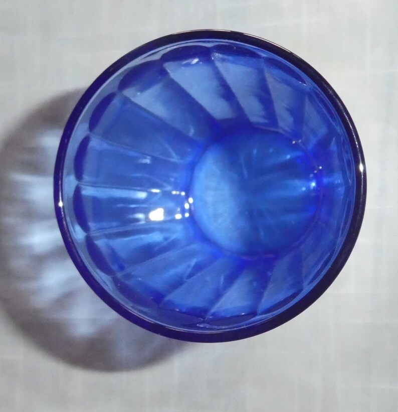 May include: A cobalt blue glass bowl with a fluted design. The bowl is empty and has a shiny finish.