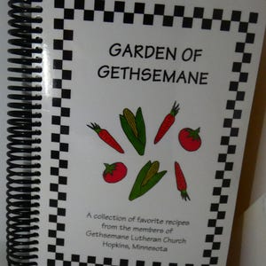 May include: A white cookbook with a black and white checkered border. The title is "Garden of Gethsemane" with a drawing of vegetables. The text below reads "A collection of favorite recipes from the members of Gethsemane Lutheran Church Hopkins, Minnesota."