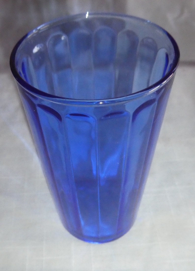 May include: A cobalt blue glass drinking glass with vertical ridges.