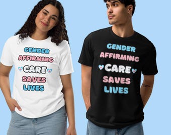 May include: Two people wearing t-shirts with the text "Gender Affirming Care Saves Lives" in pink and blue lettering with a heart symbol on either side of the word "Care". The person on the left is wearing a white t-shirt and the person on the right is wearing a black t-shirt.