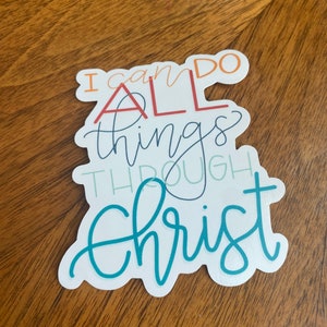 May include: A white sticker with the text "I can do all things through Christ" in colorful cursive lettering. The words "all" and "Christ" are in larger font and are highlighted in red and teal, respectively.